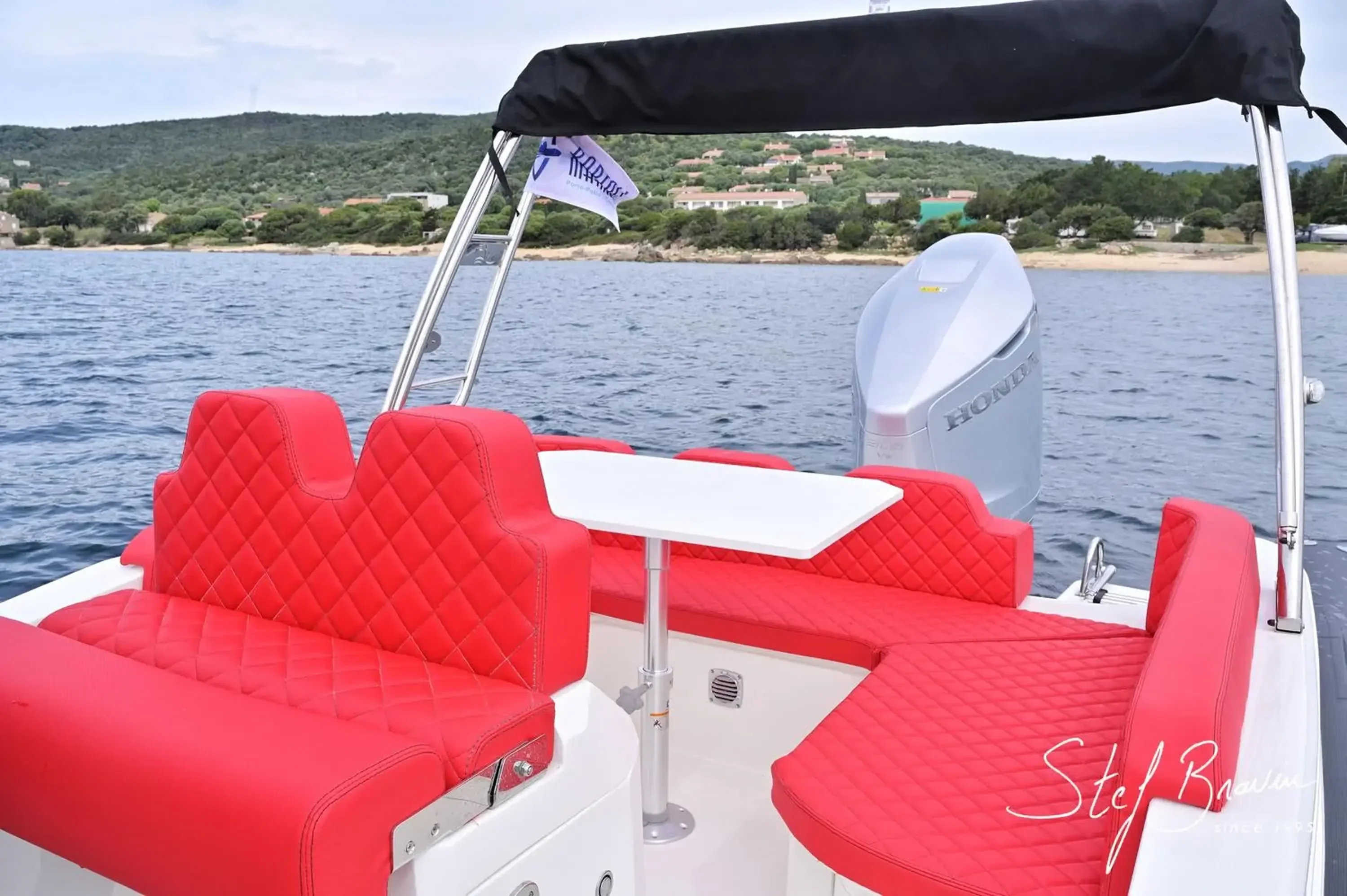 Table de cockpit et banquette rouge en U à l'arrière de l'Alpana 820, moteur Honda visible